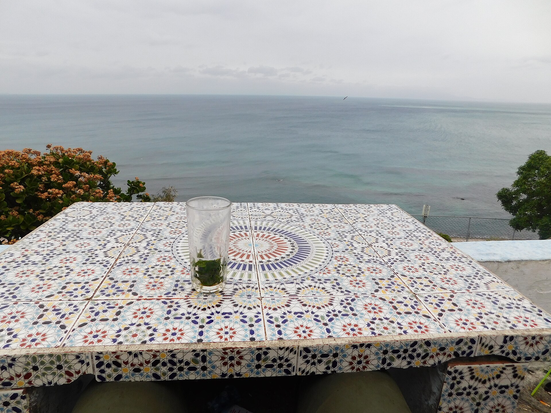 Table basse en zellige sur une terrasse dallée, face à la mer en fin de journée.